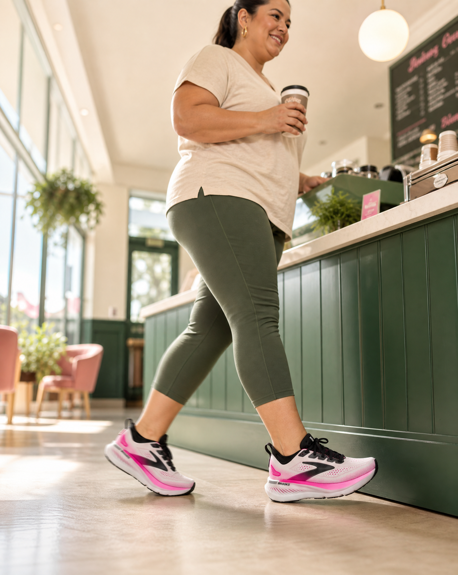 Woman walking in a cafe wearing Brooks Glycerin GTS 23 athletic shoes with pink accents