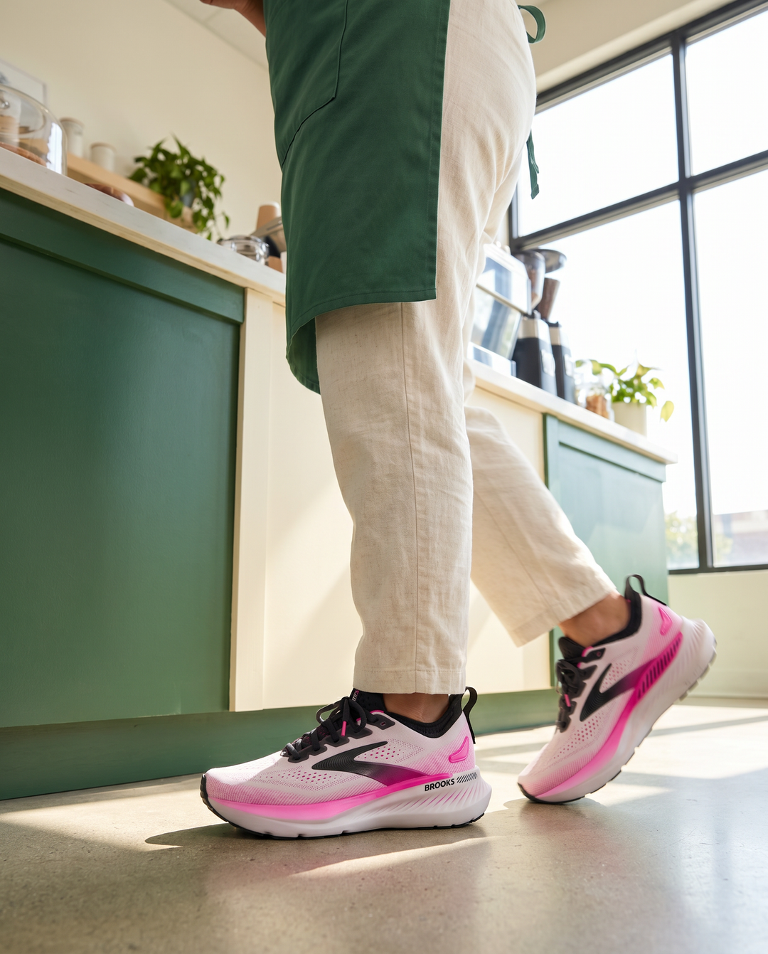 Person wearing pink and black Brooks Glycerin GTS 23 running shoes in a kitchen