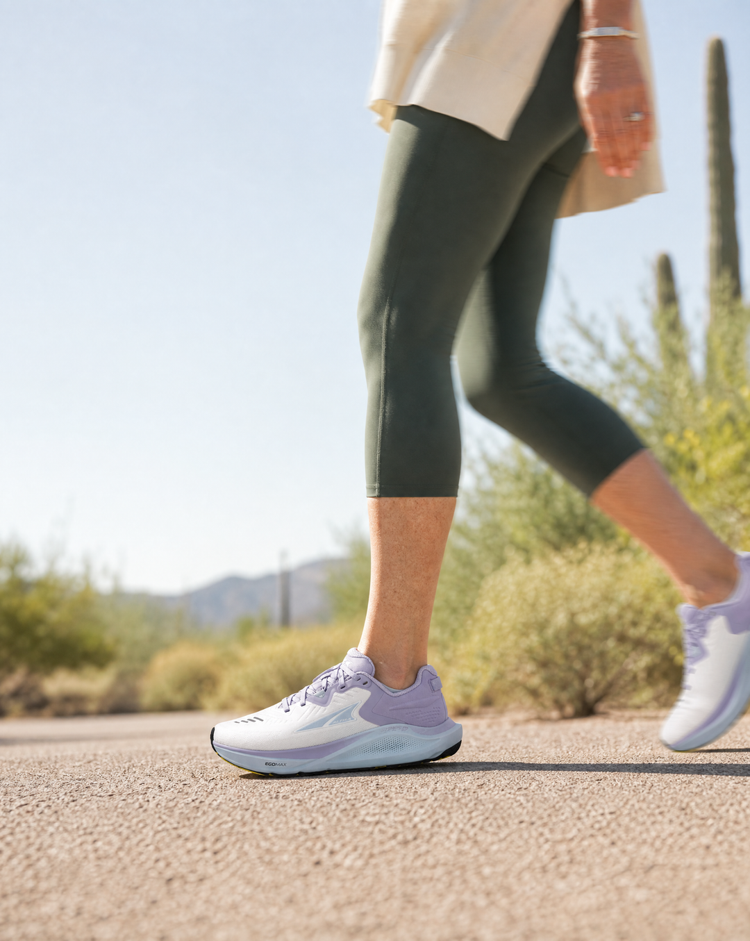 Person running on a road with a desert landscape in the background