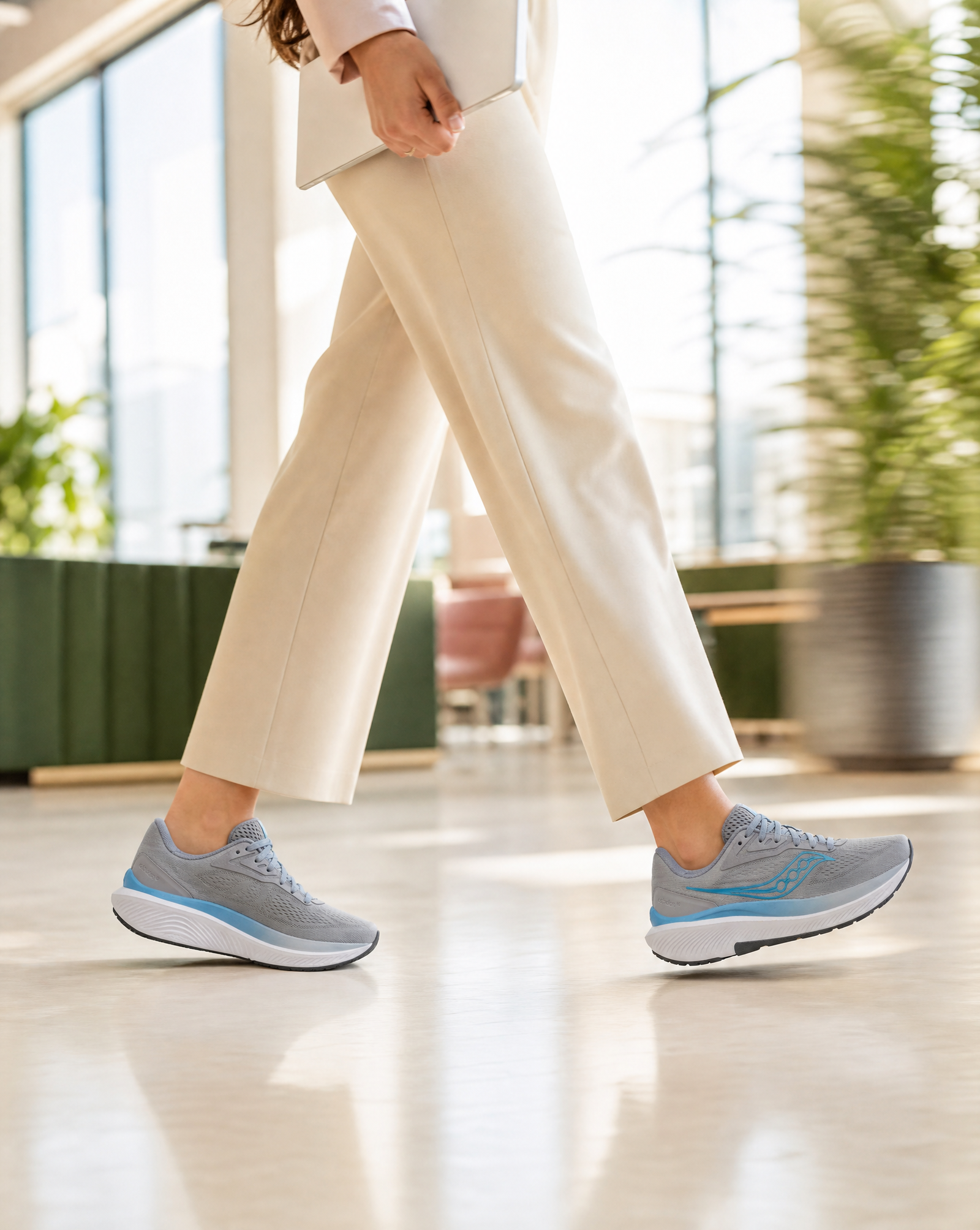 Person wearing light gray sneakers with blue accents indoors.