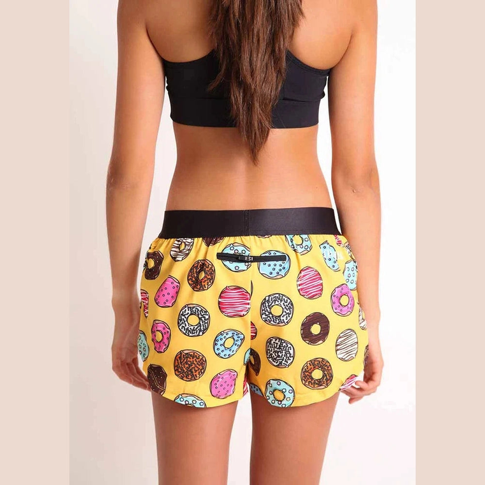 Person wearing a black sports bra and colorful donut Chicknlegs 1.5" Split Shorts – Women's on a beige background