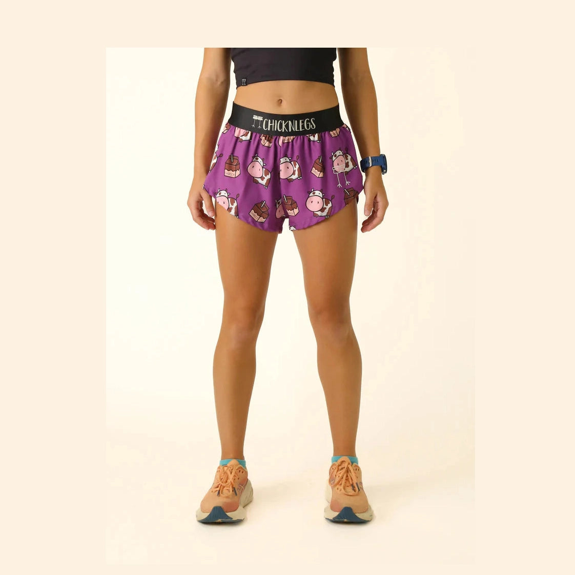 Person wearing purple Chicknlegs 1.5" Split Shorts – Women's with cartoon cow design on a beige background