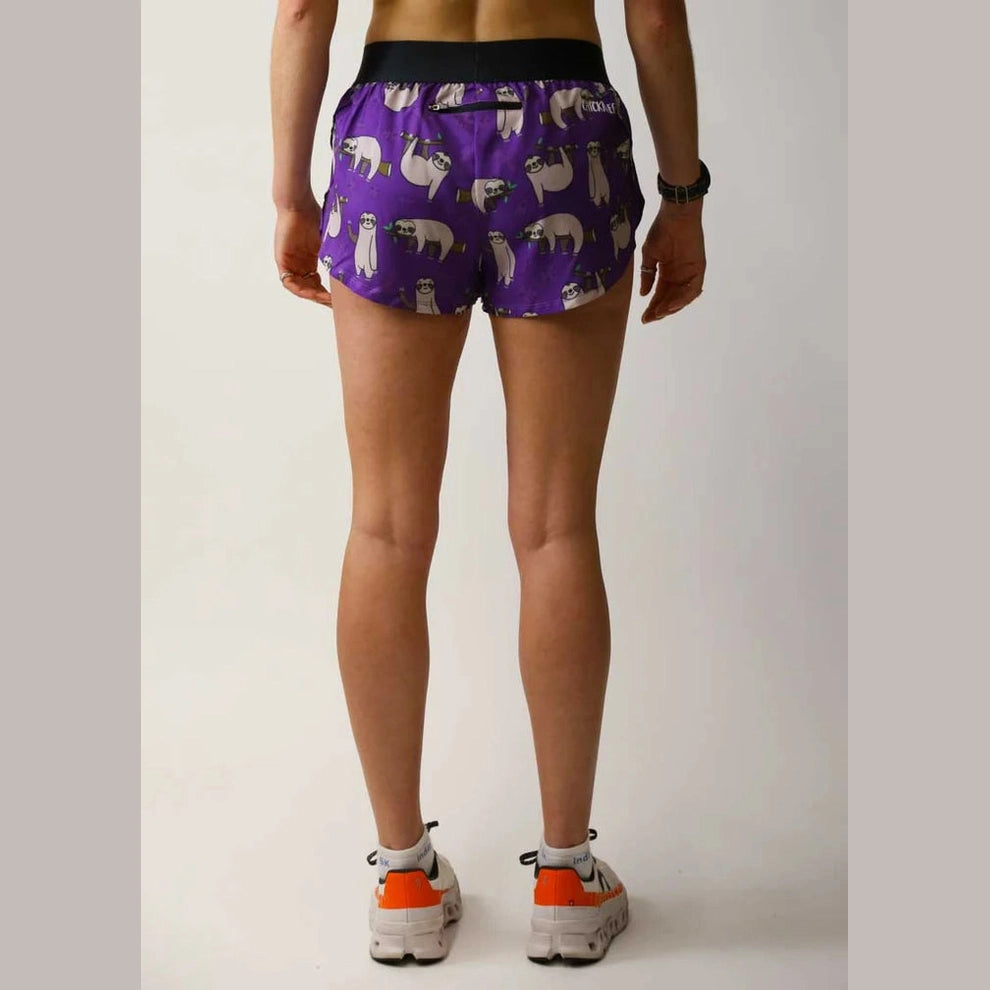 A person shown from the back wearing purple Chicknlegs 1.5" Split Shorts – Women's  with a white polar bear pattern, paired with white and orange sneakers, against a plain light gray studio background.