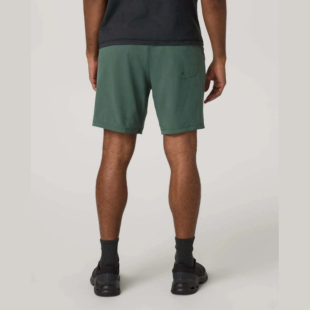 Person wearing green Vuori Kore Short 7.5" – Men's shorts on a plain background
