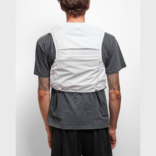 Rear view of a man wearing a light gray Justice Cordura 5L Hydration Vest over a dark gray t-shirt and black shorts, against a plain white studio background.