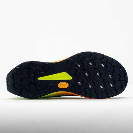 The outsole of a trail running shoe, featuring a black textured tread pattern with a bright neon yellow-green accent and an orange Vibram logo badge.