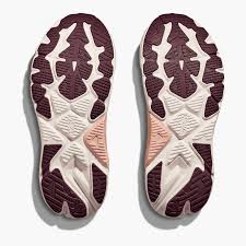 Top-down view of a pair of athletic shoes showing the textured outsoles in dark burgundy, cream, and light pink.