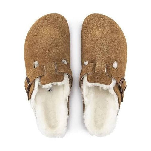 A pair of tan suede Birkenstock Boston Shearling clogs with a white shearling lining, shown from a top-down view on a white background.
