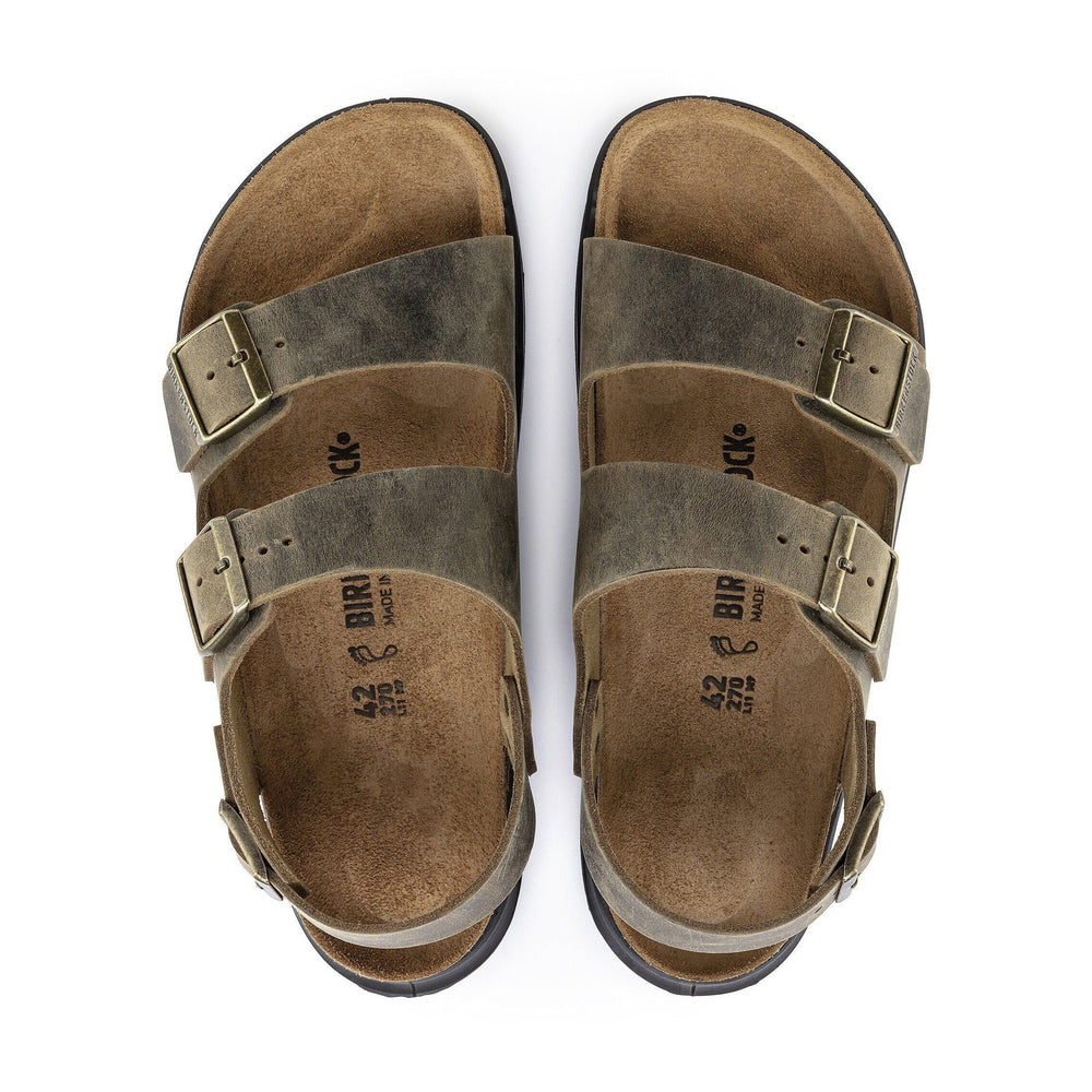 A pair of Birkenstock Milano Crosstown sandals in a distressed olive-brown leather finish with bronze-toned metal buckles, shown from a top-down view on a white background.