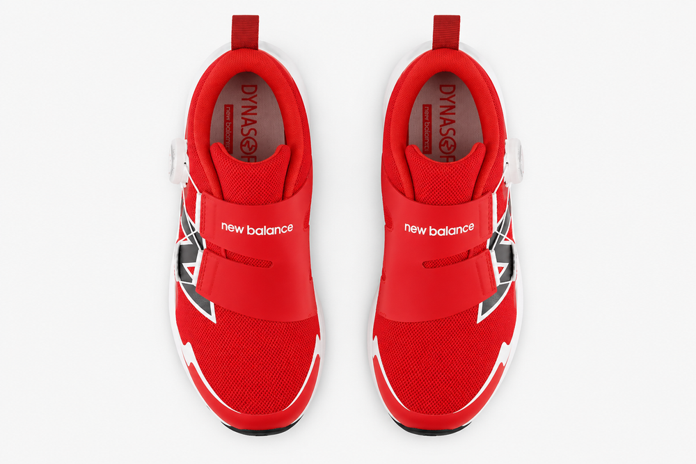 A pair of red New Balance Reveal V4 BOA – Kids' sneakers shown from a top-down view on a light gray background. The shoes feature a red mesh upper, a hook-and-loop strap closure, and white and black graphic accents.