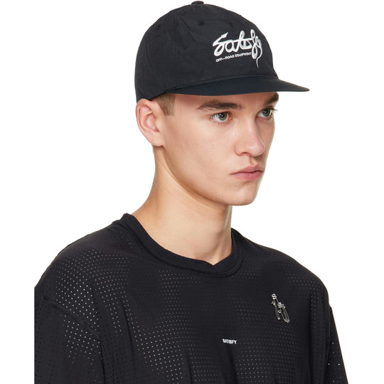 A man wearing a black Flitesilk 5 Panel Pinch Cap with a white embroidered and a black perforated crewneck shirt, shown in a side-profile view against a white background.