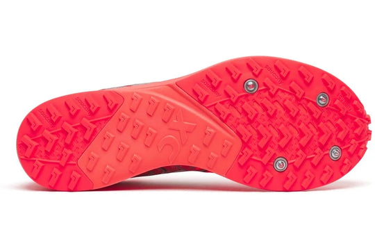 A close-up bottom view of a red athletic shoe sole with textured tread and three metal spike studs, shown on a white background.