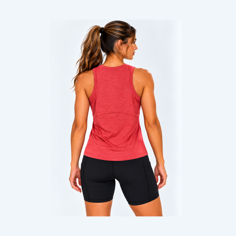 A woman shown from the back wearing a heathered coral-red racerback tank top and black bike shorts against a light gray studio background.