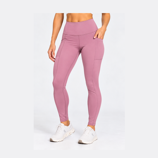 A model wearing high-waisted, form-fitting Purestretch 7" Tight Shorts in a dusty rose pink color with side pockets, paired with white sneakers, against a plain white studio background.