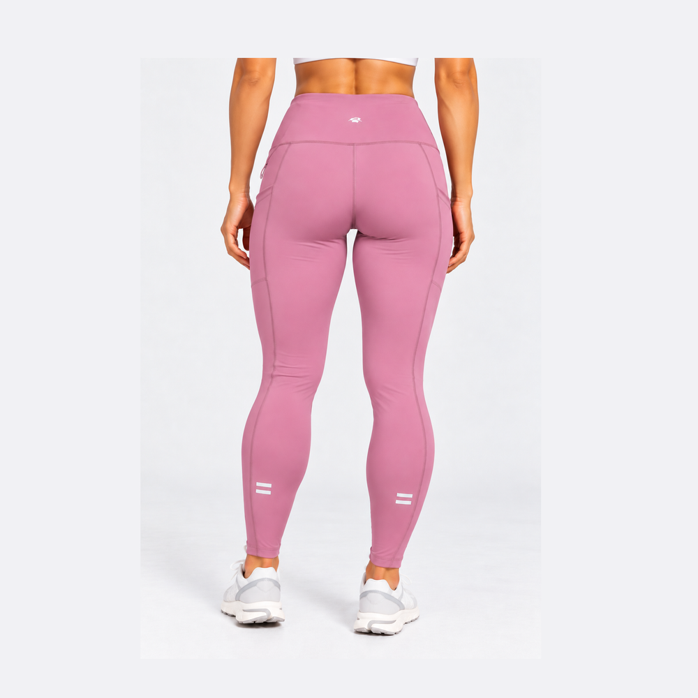 A model shown from the back wearing high-waisted pink Purestretch 7" Tight Shorts with white sneakers, set against a plain light gray studio background.