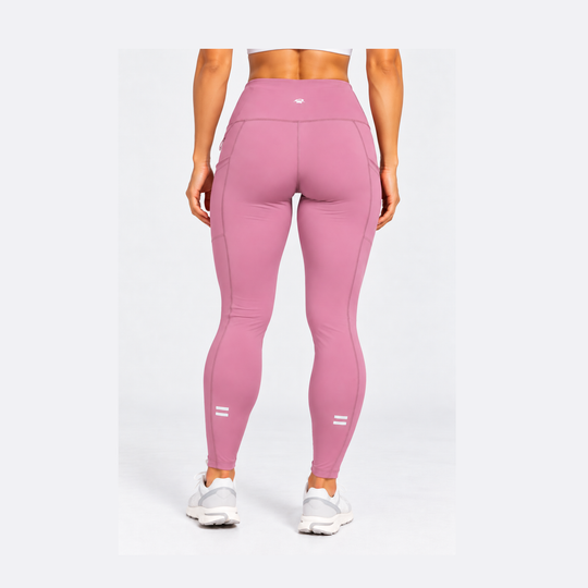 A model shown from the back wearing high-waisted pink Purestretch 7" Tight Shorts with white sneakers, set against a plain light gray studio background.