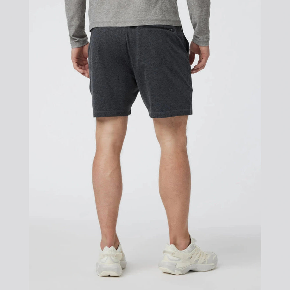 A person shown from the back wearing dark charcoal gray Vuori Ponto Short – Men's athletic shorts, a heather gray long-sleeve top, and off-white sneakers against a light gray studio background.