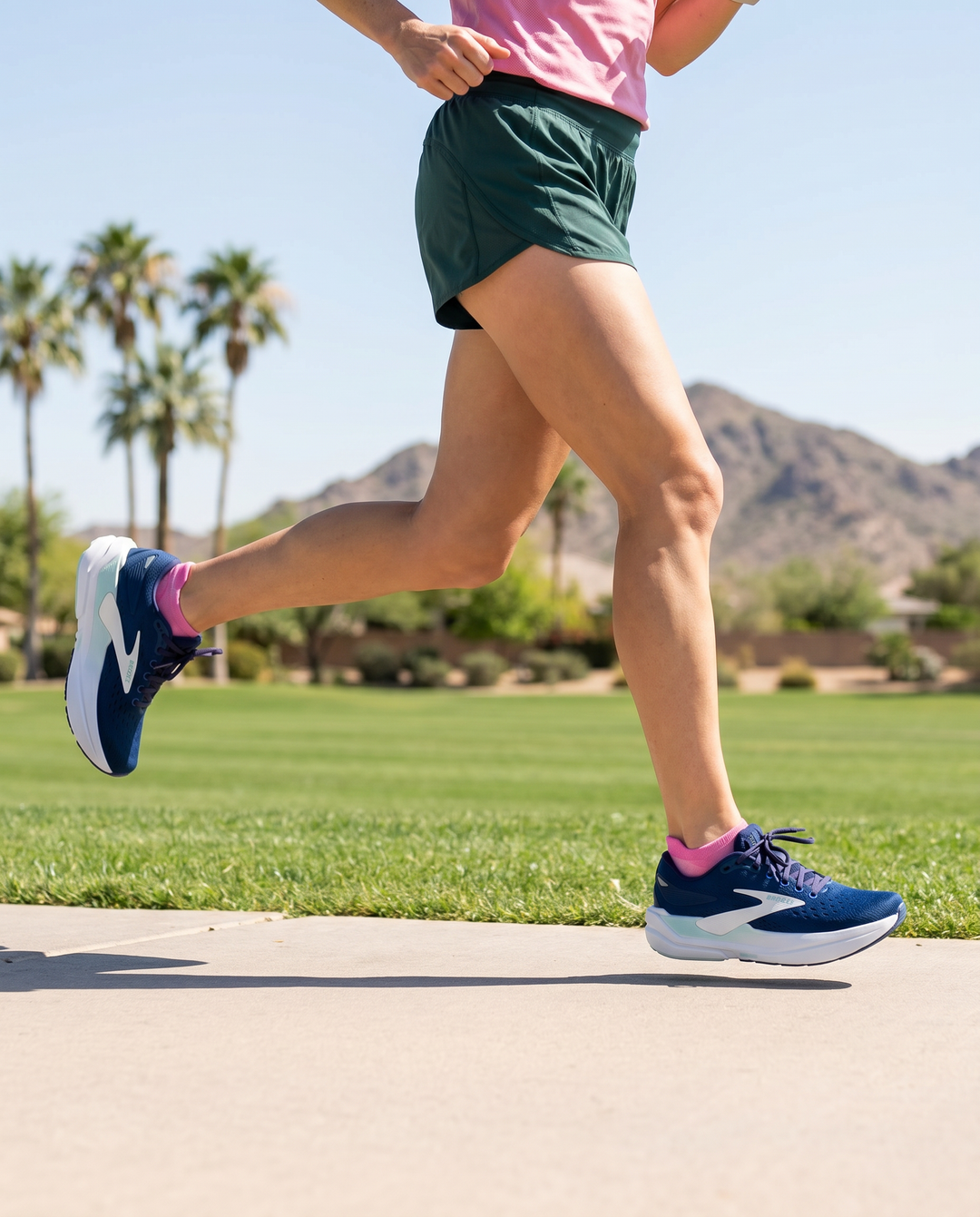 Person running in Brooks Max 3 shoe on a path with palm trees and mountains in the background